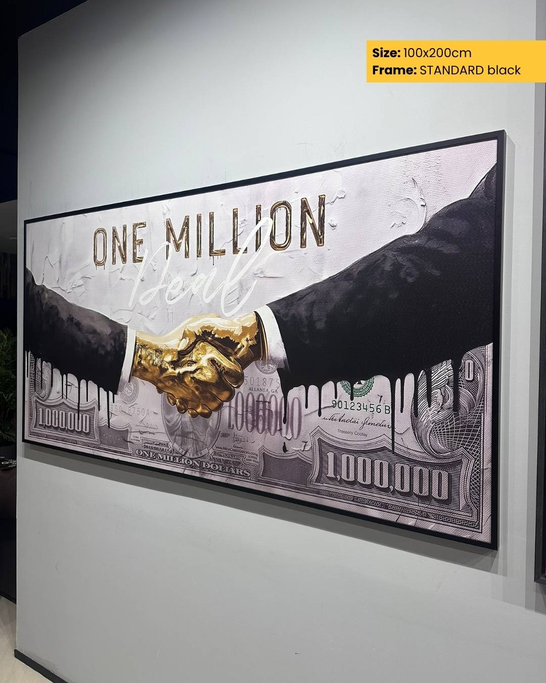 Framed artwork of two hands shaking with a gold handshake on a $100 bill background.