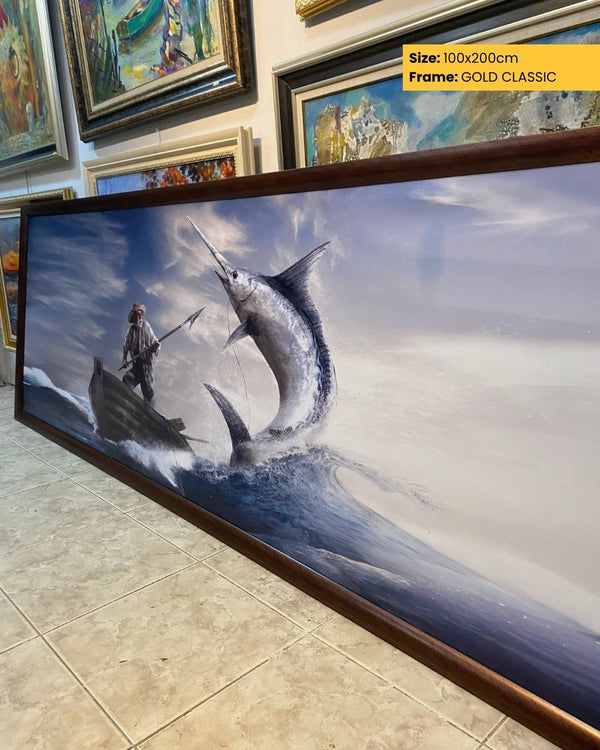 Framed artwork of a fisherman and a large fish on a beach with other artworks in the background.