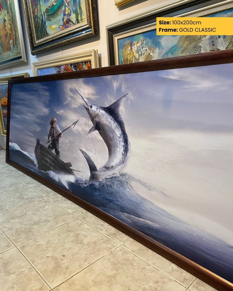 Framed artwork of a fisherman and a large fish on a beach with other artworks in the background.