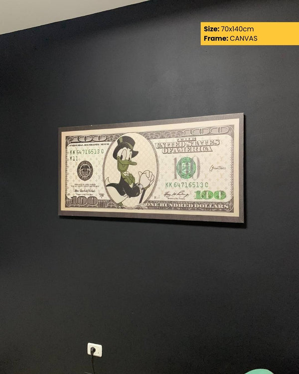Framed artwork of a $100 bill with a cartoon character on a black wall.