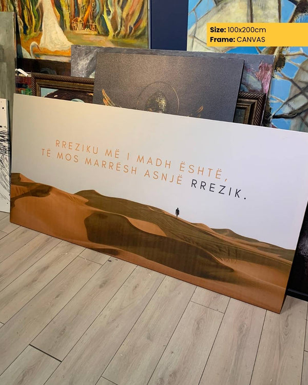Canvas print with desert landscape and text on a wooden floor, surrounded by other artworks.
