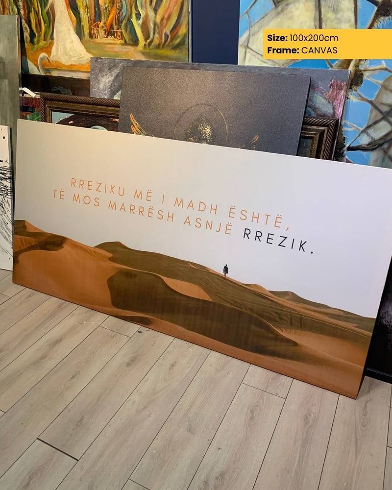 Canvas print with desert landscape and text on a wooden floor, surrounded by other artworks.