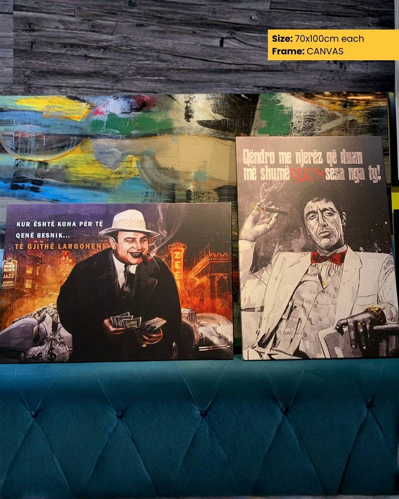 Three framed artworks on a teal sofa against a wooden wall.