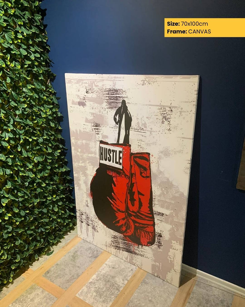 Canvas print with a graphic design of a person holding boxing gloves and the word 'HUSTLE' on a textured background, leaning against a wall.