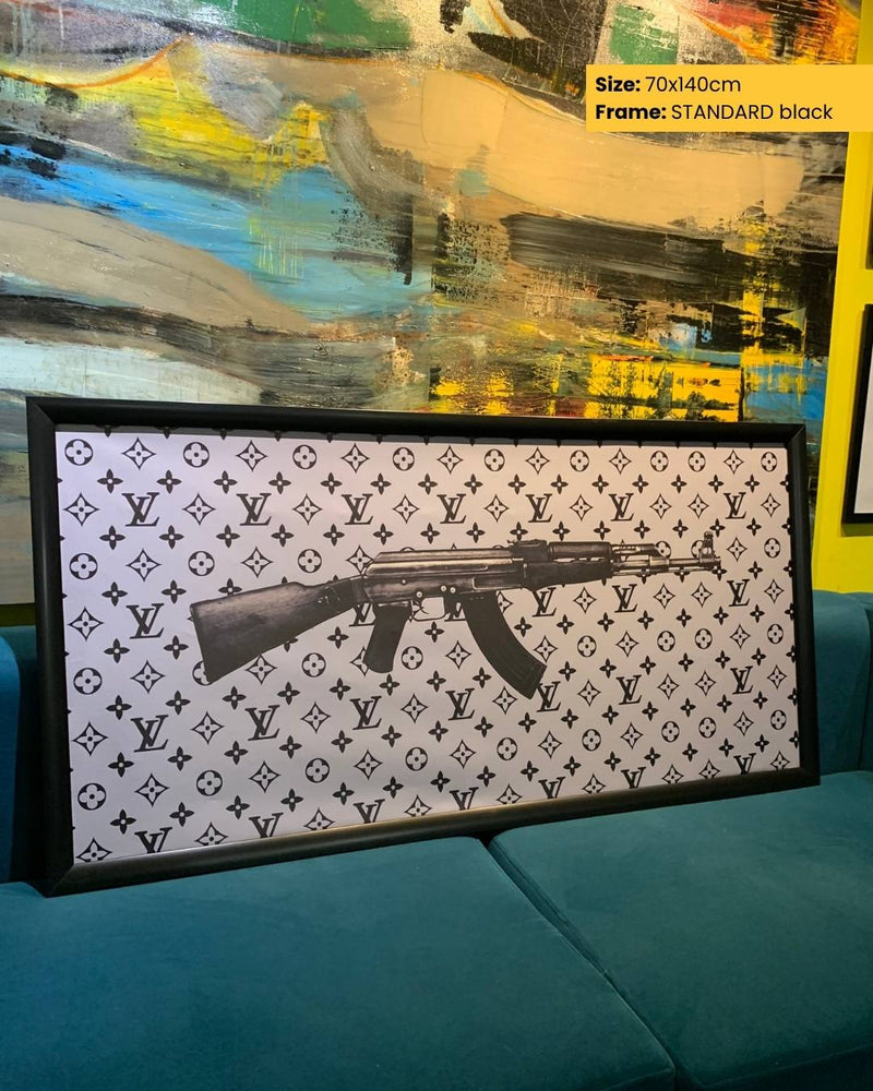 Framed artwork with a gun design on a patterned background, displayed on a teal sofa.