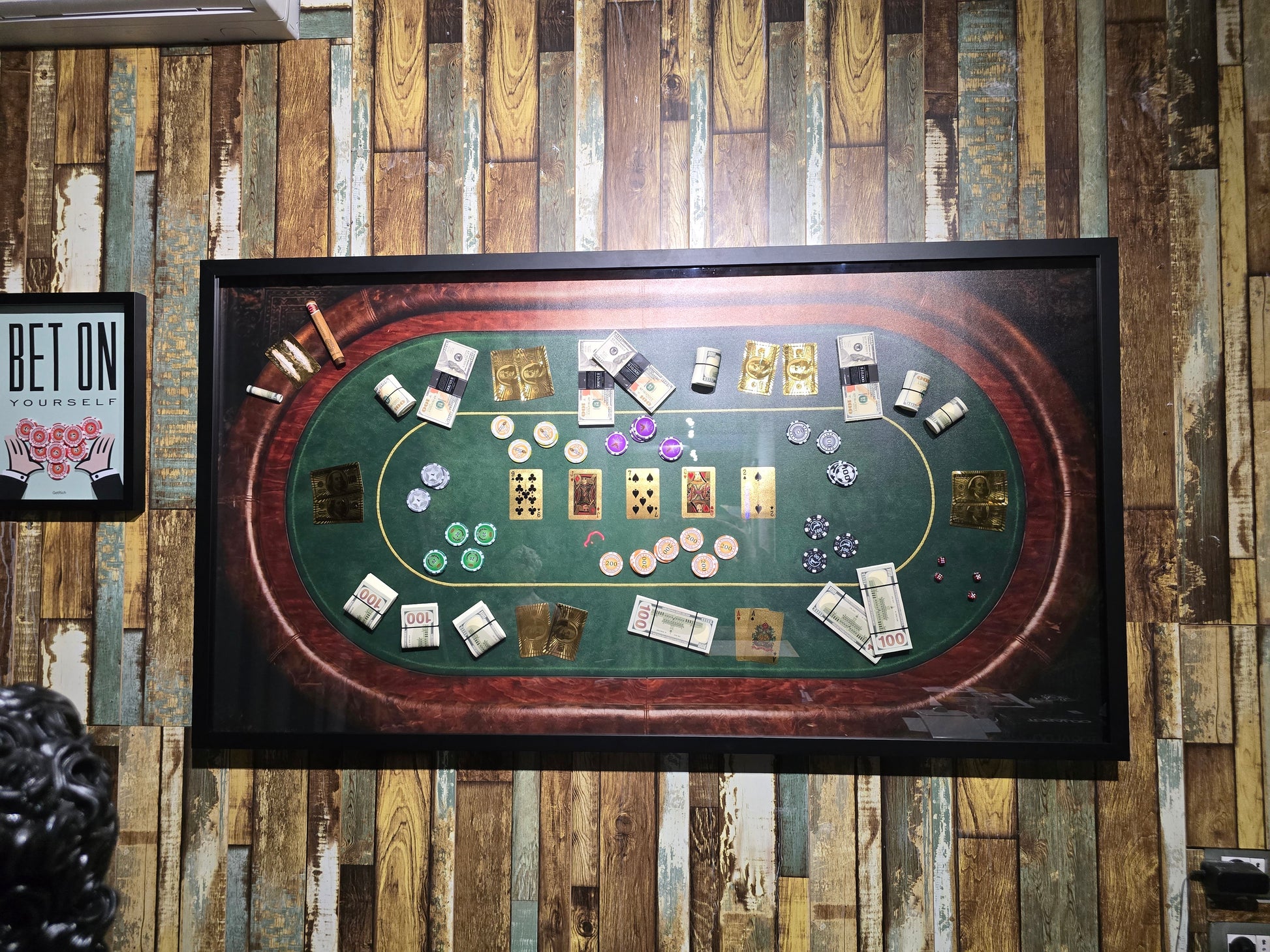 Framed picture of a craps table with dice and chips on a wooden wall.