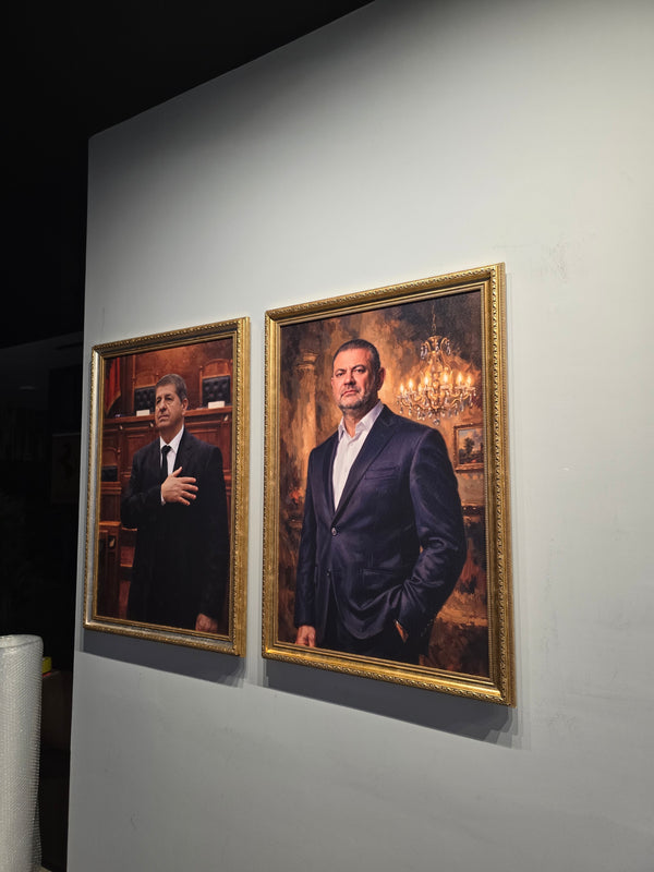 Two framed portraits of a man in formal attire on a white wall.