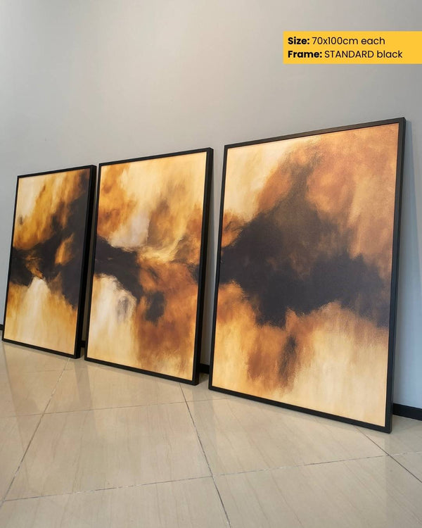Three abstract art pieces with a black frame on a light gray wall.