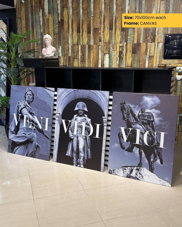 Three artistic prints with Roman-themed figures displayed on a stand against a wooden wall.
