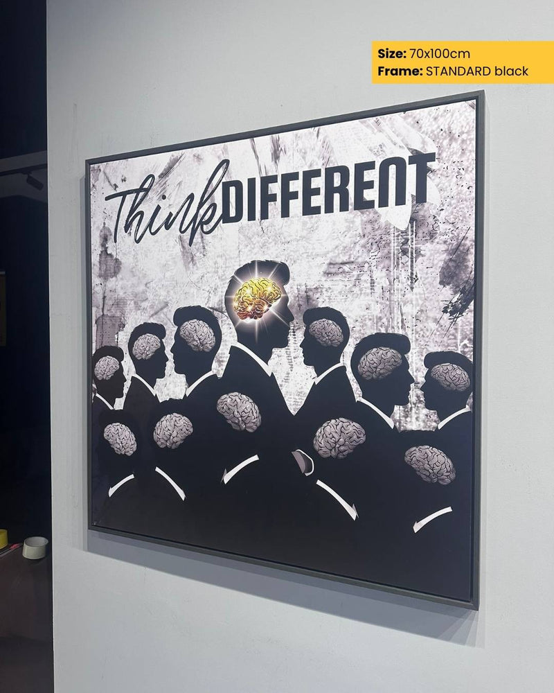 Framed artwork with 'Think DIFFERENT' text and silhouettes of people with brains on a white wall.