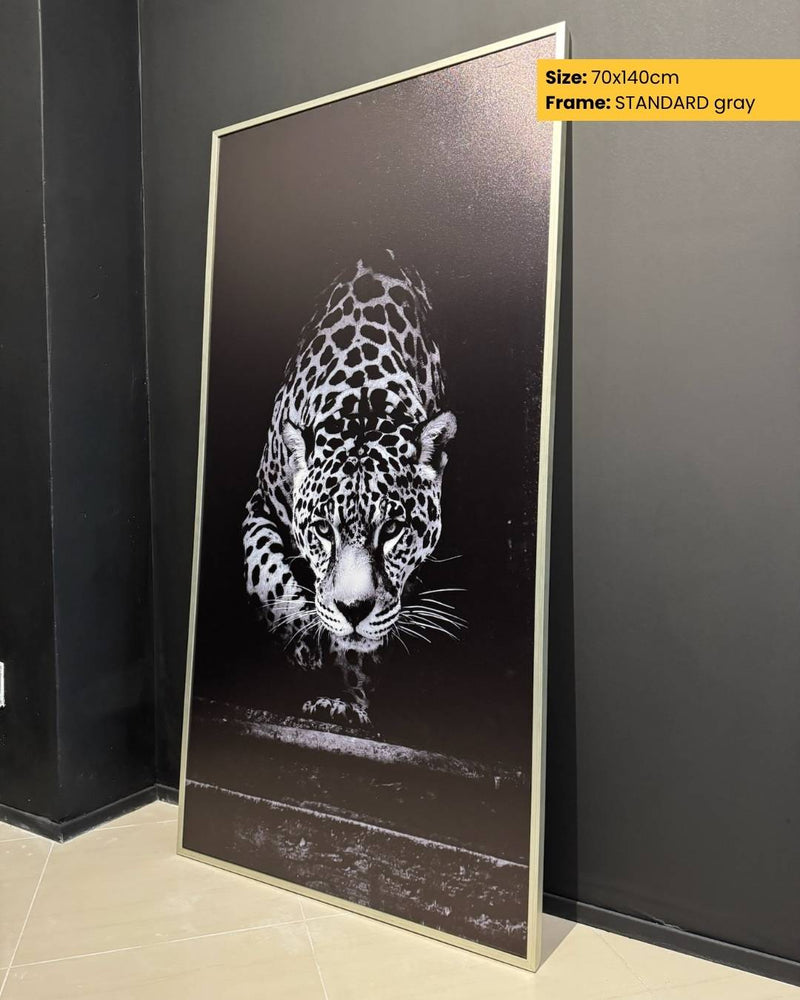 Framed artwork of a leopard on a dark background, leaning against a wall.