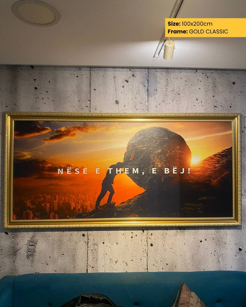 Framed artwork with a sunset scene and text on a concrete wall.