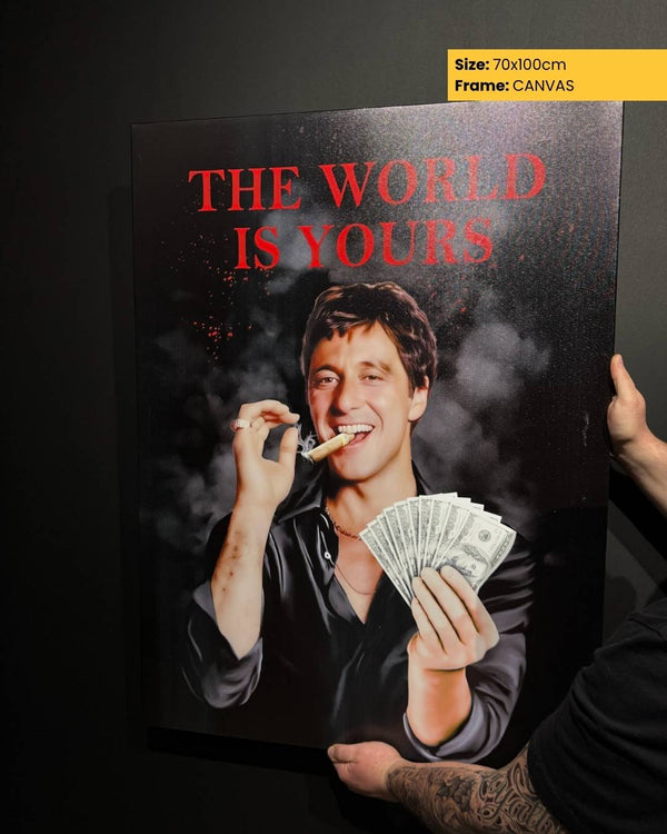 Person holding a canvas print with a man smoking and holding money, text 'The World is Yours'.