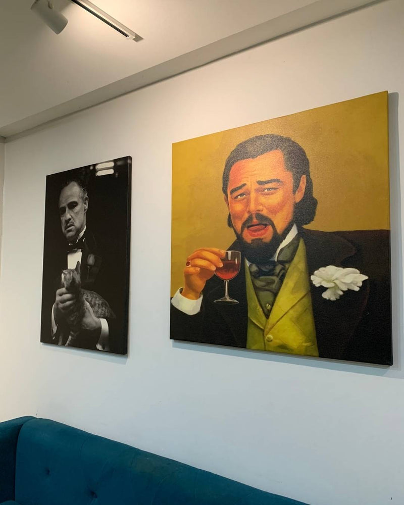 Two paintings of a man in formal attire, one holding a glass of wine, on a white wall.