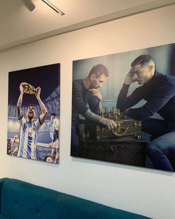 Two large wall art prints of a soccer player and two men playing chess on a white wall.