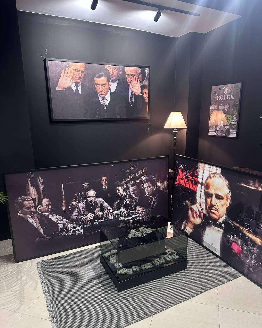 Display of framed movie posters and a TV screen showing a scene from a film in a room with dark walls.