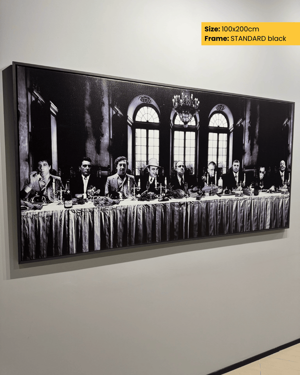 Framed black and white artwork of a formal gathering with people around a long table on a wall.
