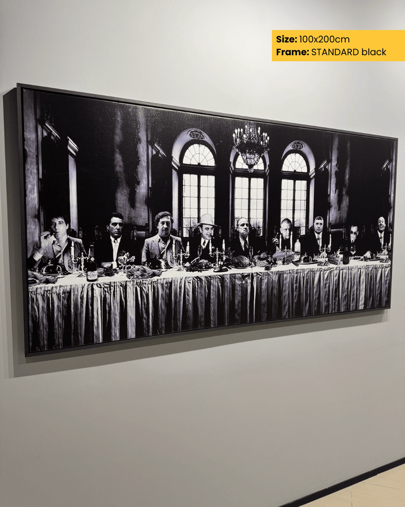 Framed black and white artwork of a formal gathering with people around a long table on a wall.