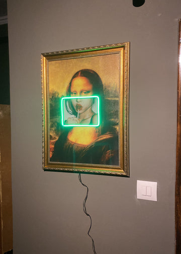 Framed artwork with a green glowing effect on a gray wall.