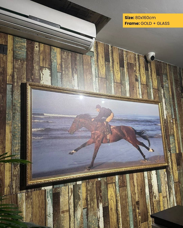 Framed picture of a horse on a beach displayed on a wooden wall.