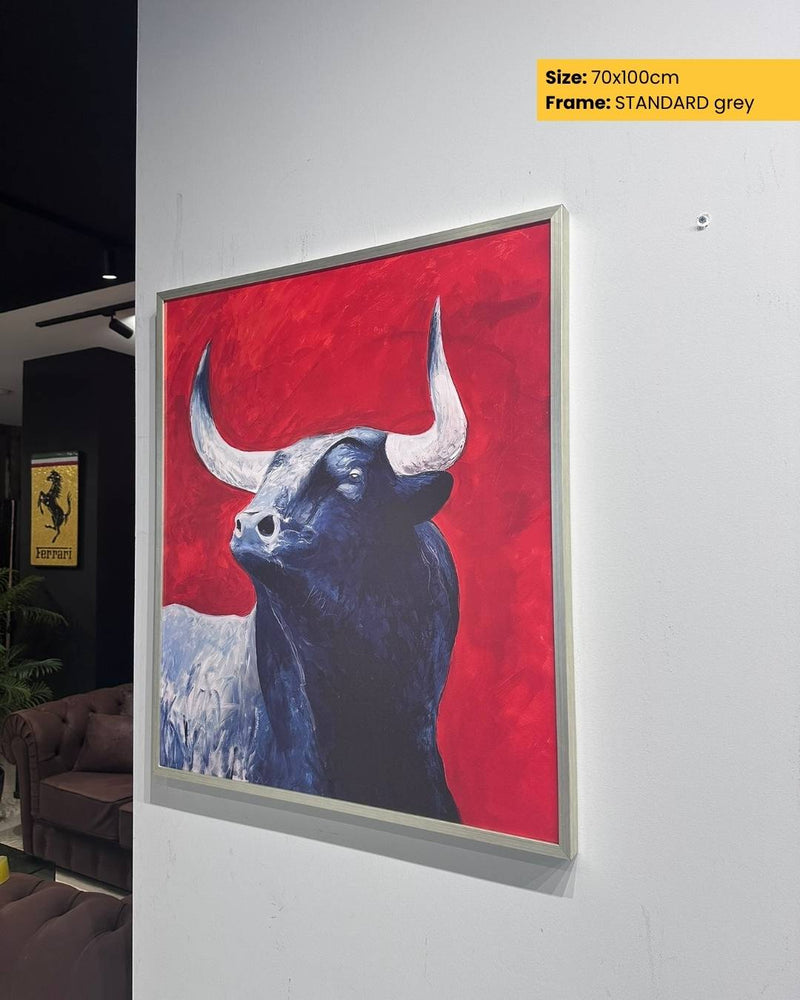 Framed artwork of a bull on a red background in an indoor setting