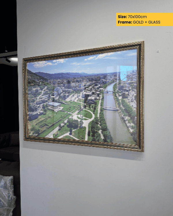 Framed aerial view of a cityscape with gold frame and glass on a white wall.