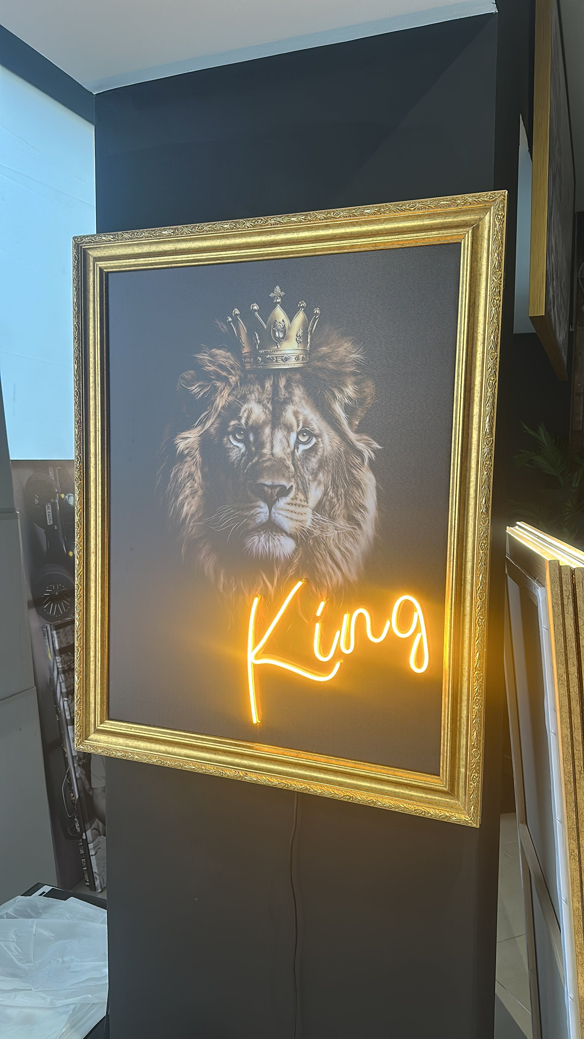 Framed artwork with a lion's head and the word 'King' in neon lights.