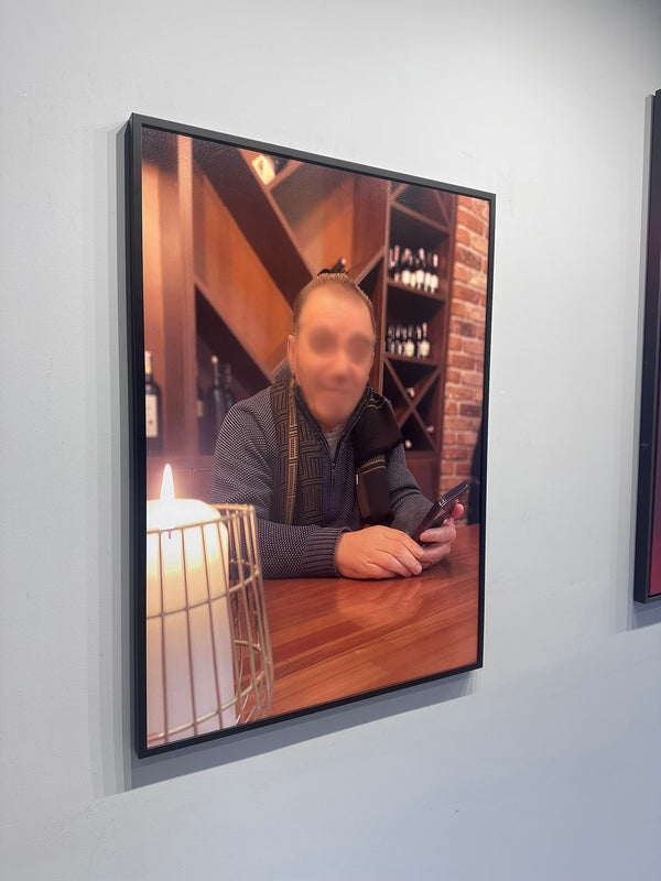 Person sitting at a table with a phone, framed picture on a wall