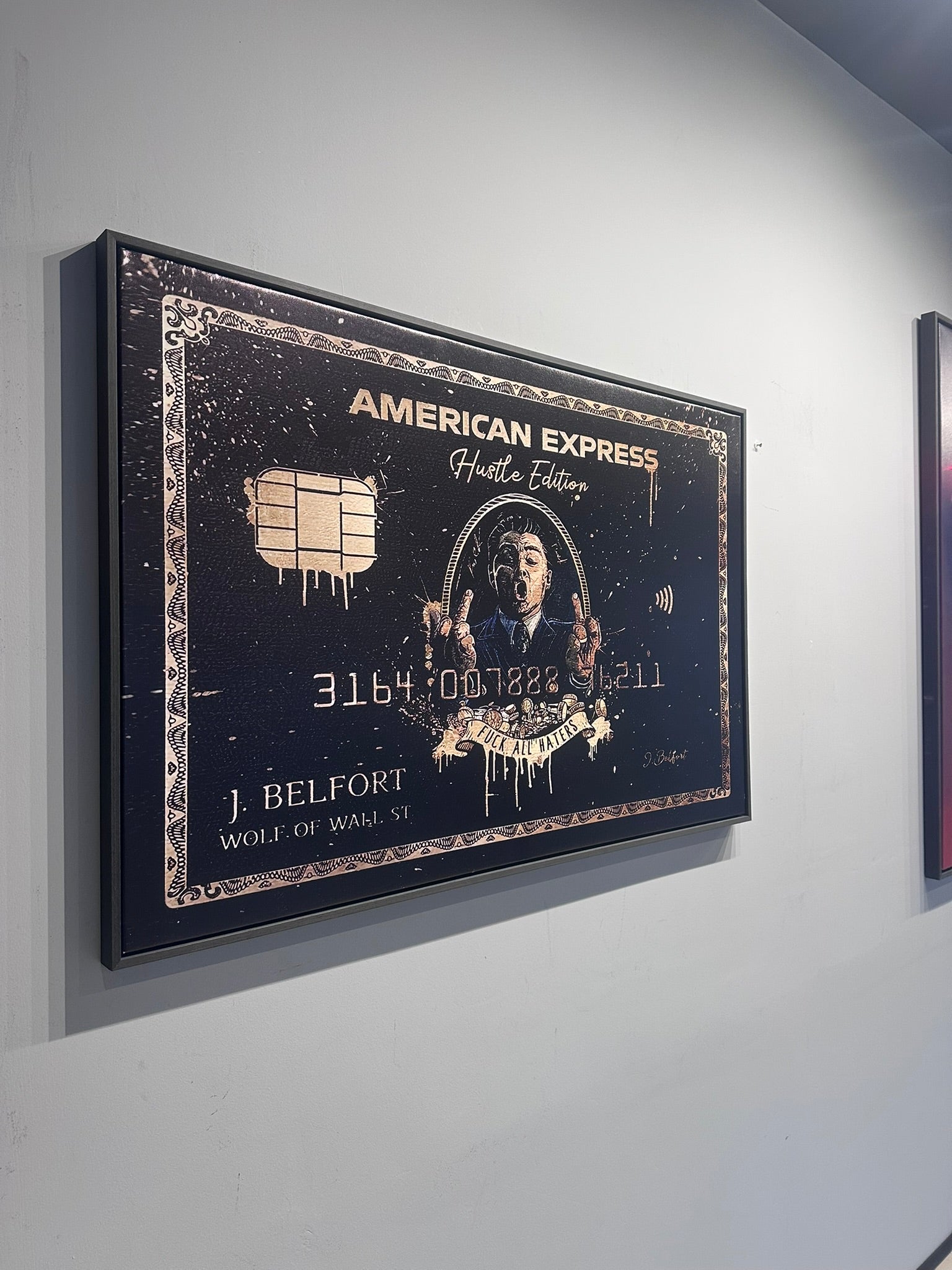 Framed artwork of a stylized American Express card on a wall