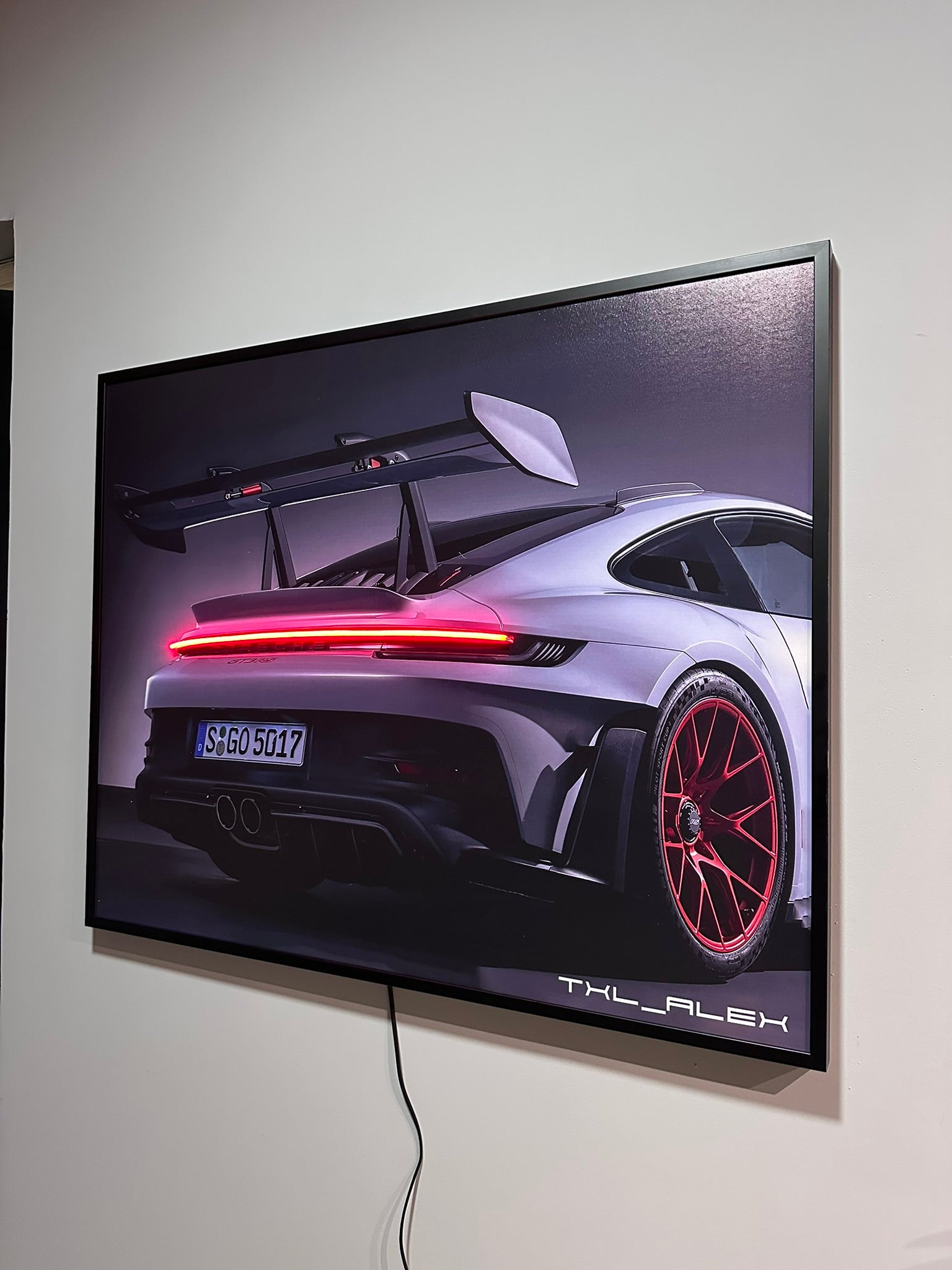 Car on a screen with visible branding on a white wall