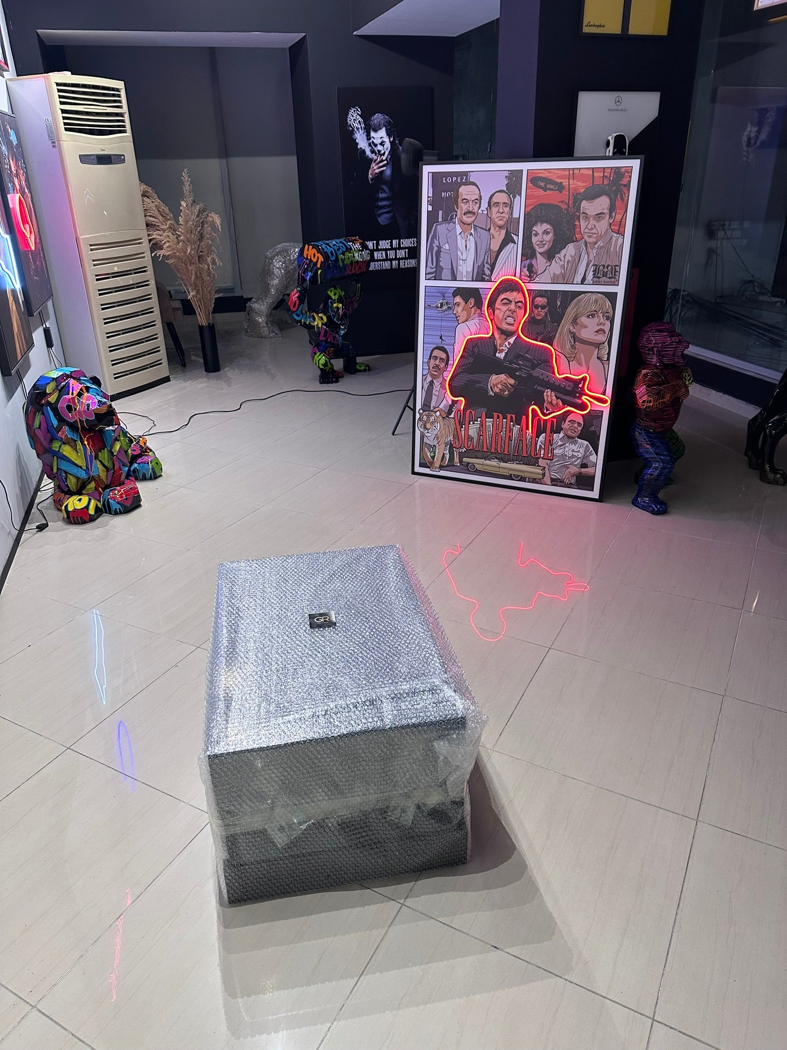 Room with a large speaker on the floor, colorful decorations, and a framed collage of people.