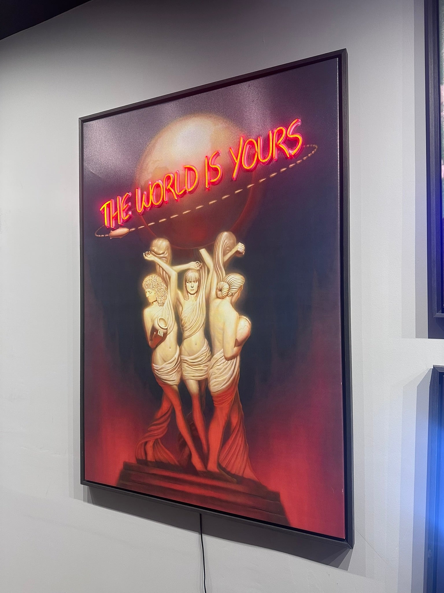 Neon sign with 'The World is Yours' text and three figures on a dark background