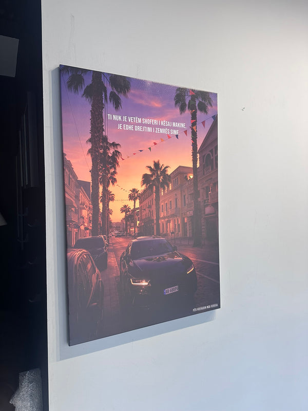 Canvas print of a city street scene with palm trees and a sunset, mounted on a wall.