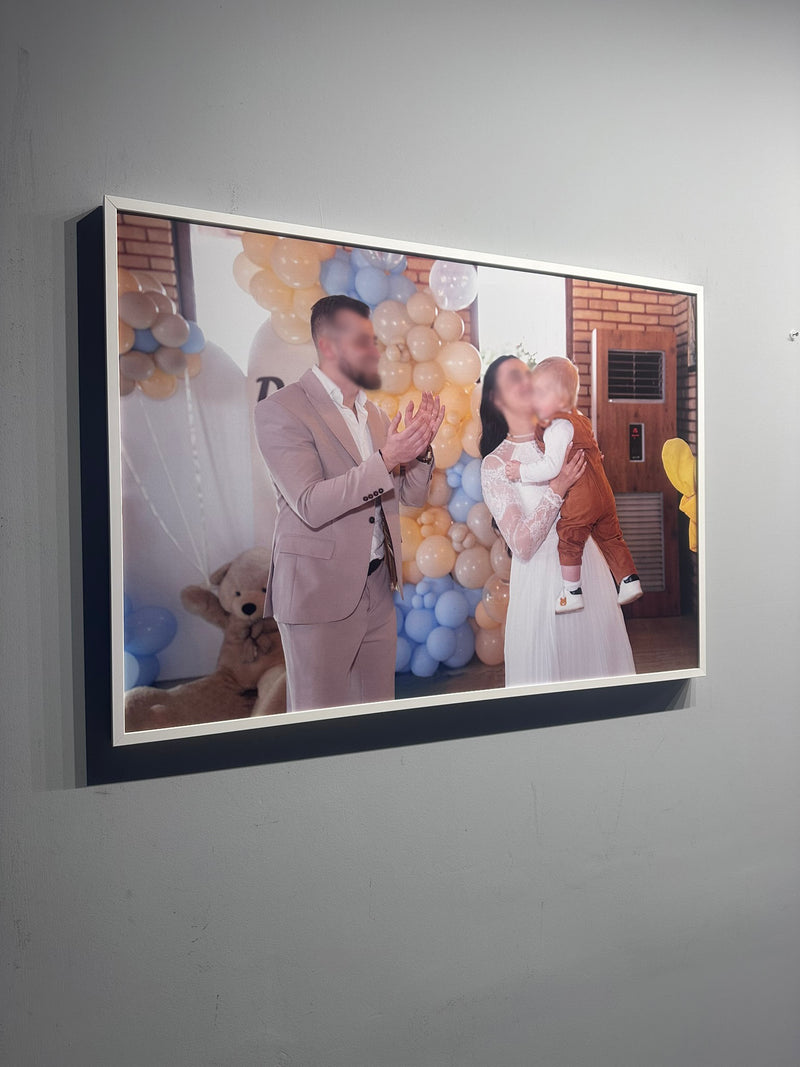 Framed photograph of a couple with a child against a gray wall.