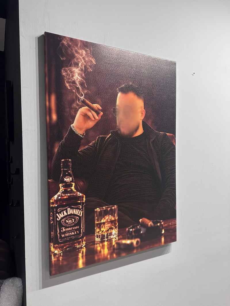 Man smoking a cigar with a Jack Daniel's whiskey bottle and glass on a table, displayed on a wall.