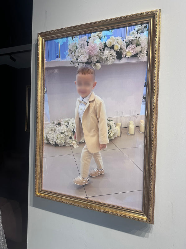 Child in formal attire standing in front of a decorated wall with flowers and candles.