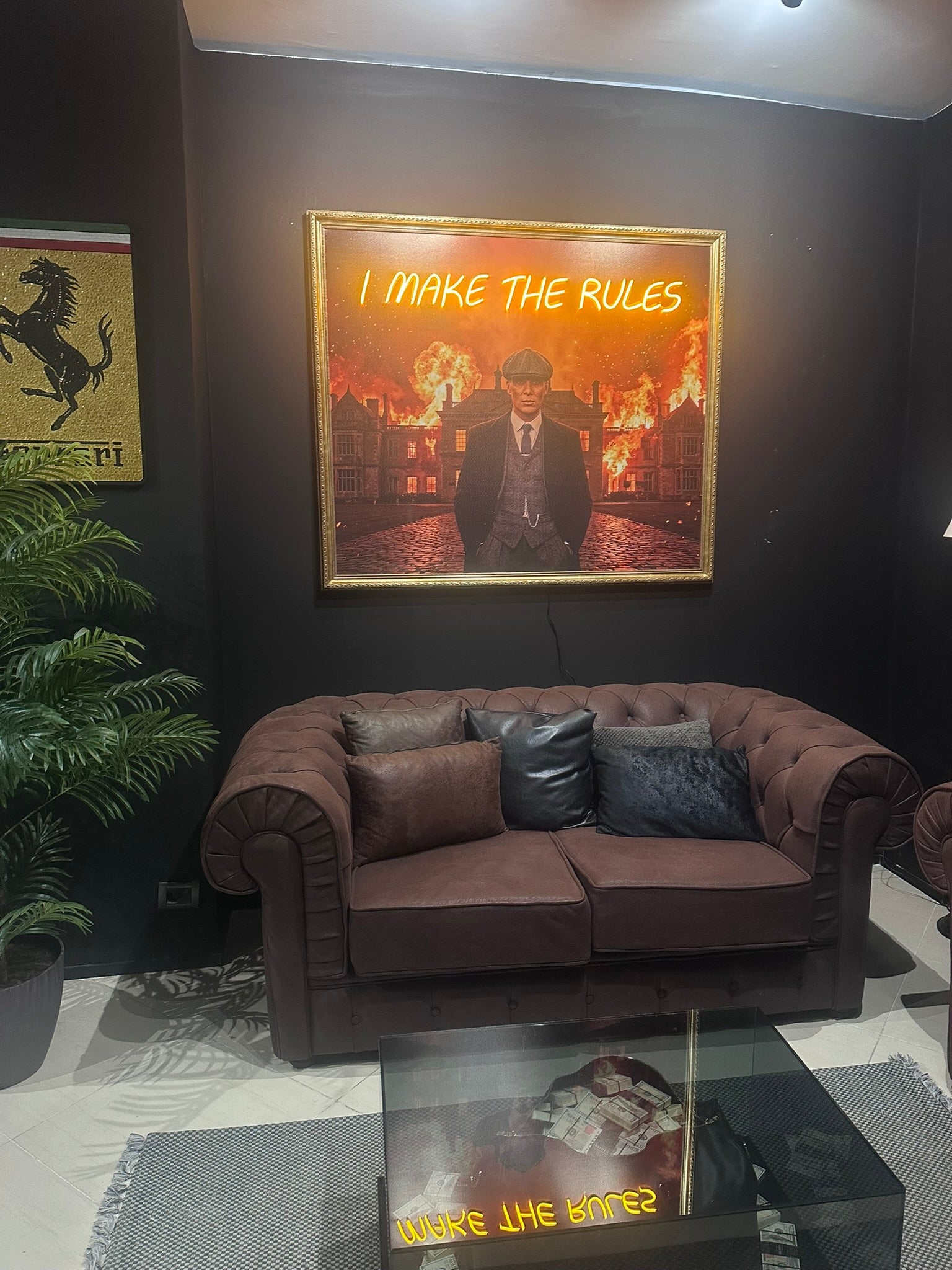 Living room with a brown sofa, framed picture on the wall, and a plant.