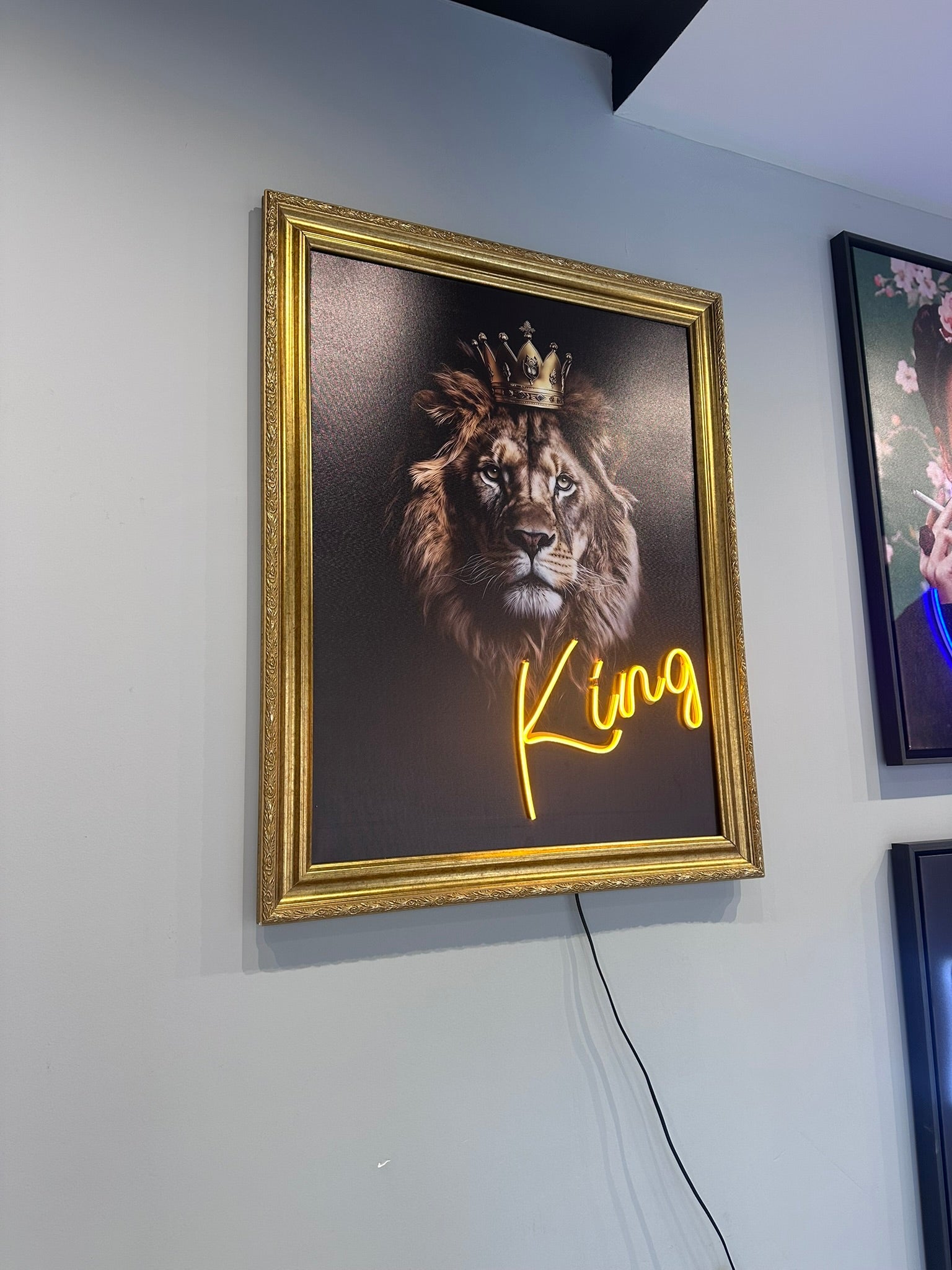 Framed artwork of a lion with a crown and 'King' text on a wall.