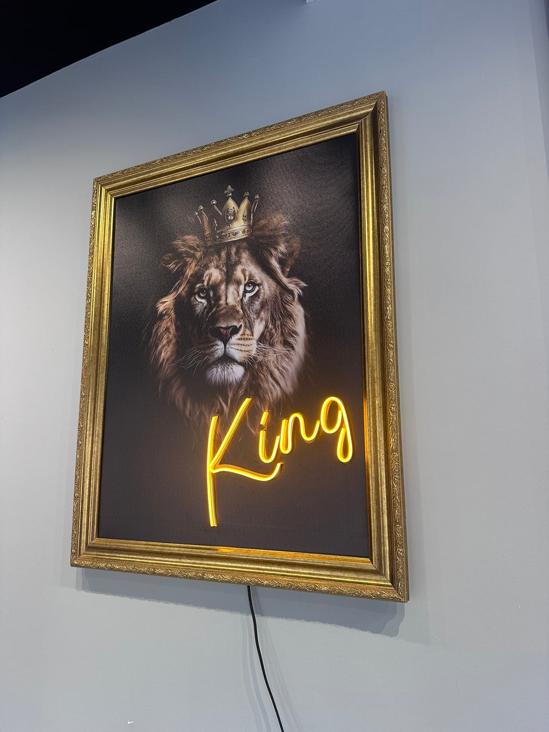 Framed artwork of a lion with a crown and 'King' text on a wall.