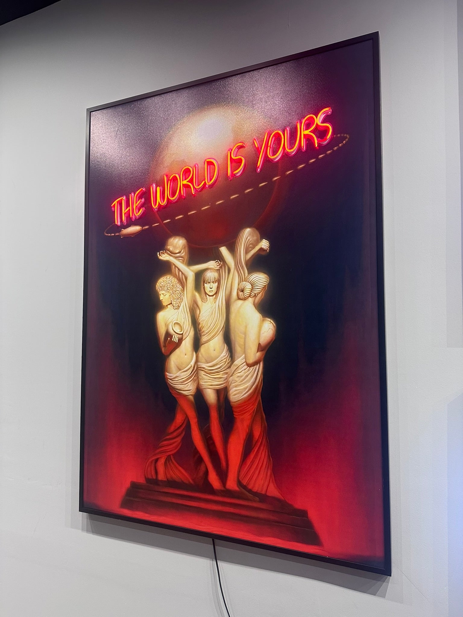Neon sign with 'The World is Yours' text and classical figures on a dark background