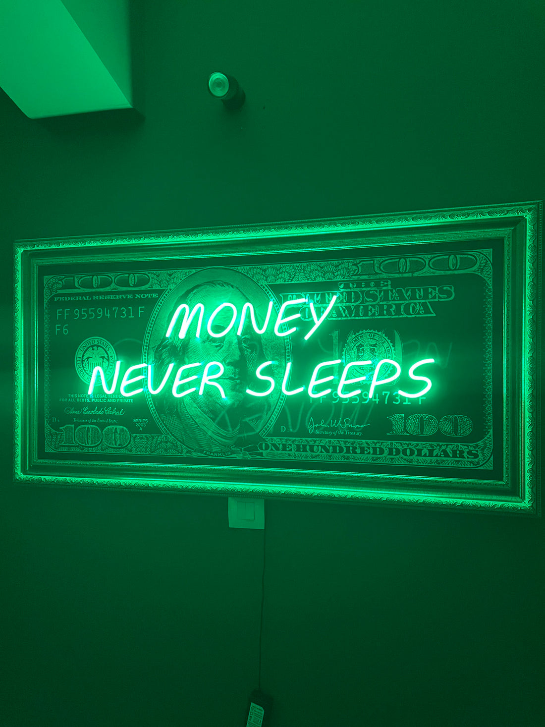 Neon sign with 'Money Never Sleeps' text on a green background