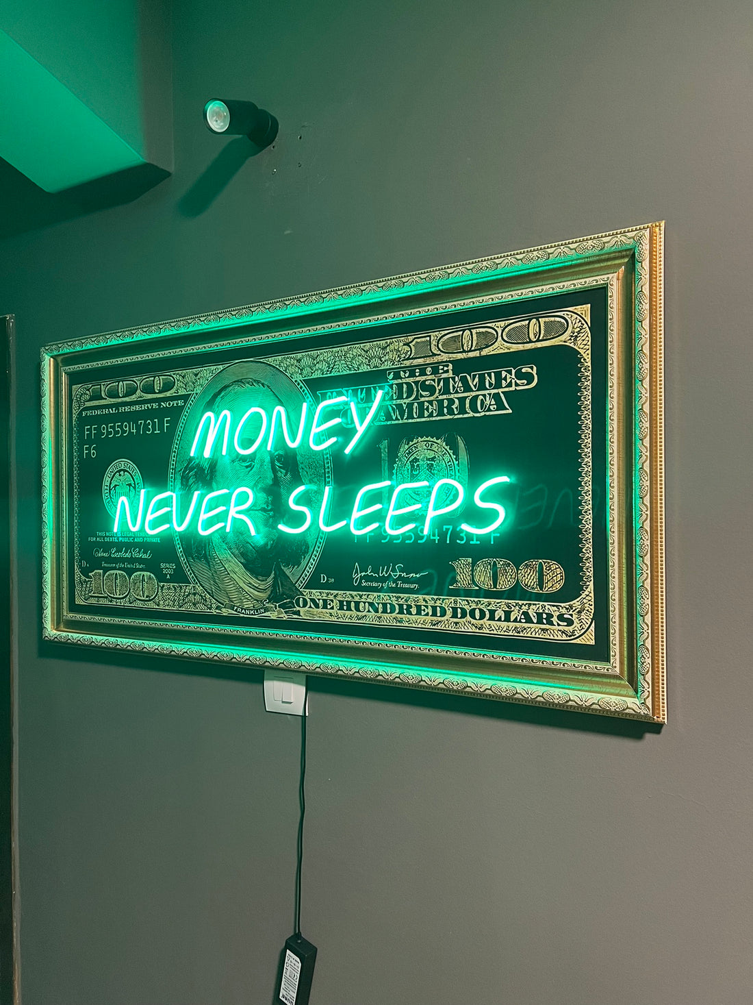 Neon sign with 'Money Never Sleeps' text on a green background