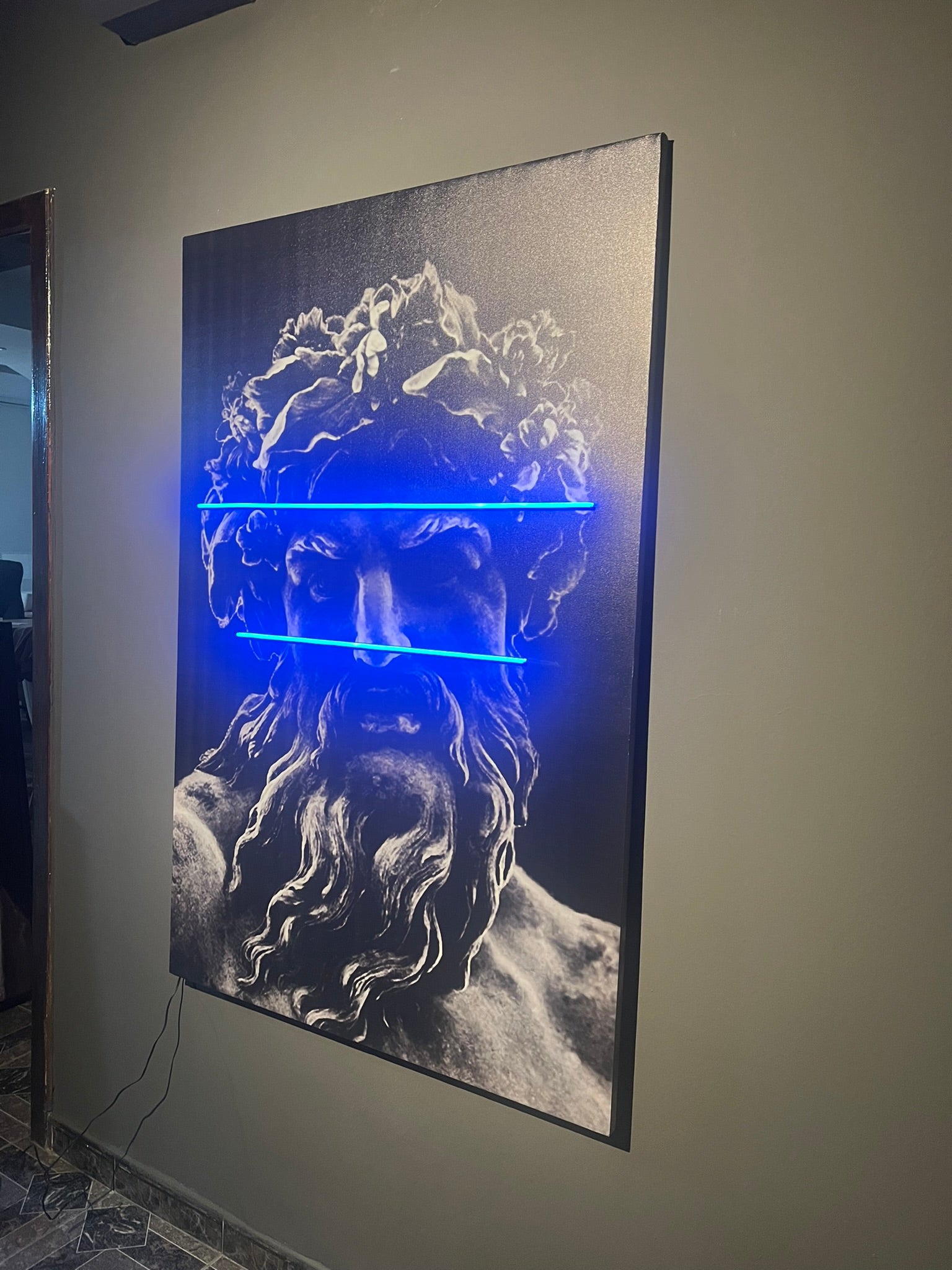 Artistic depiction of a face with blue light on a dark background, mounted on a wall.