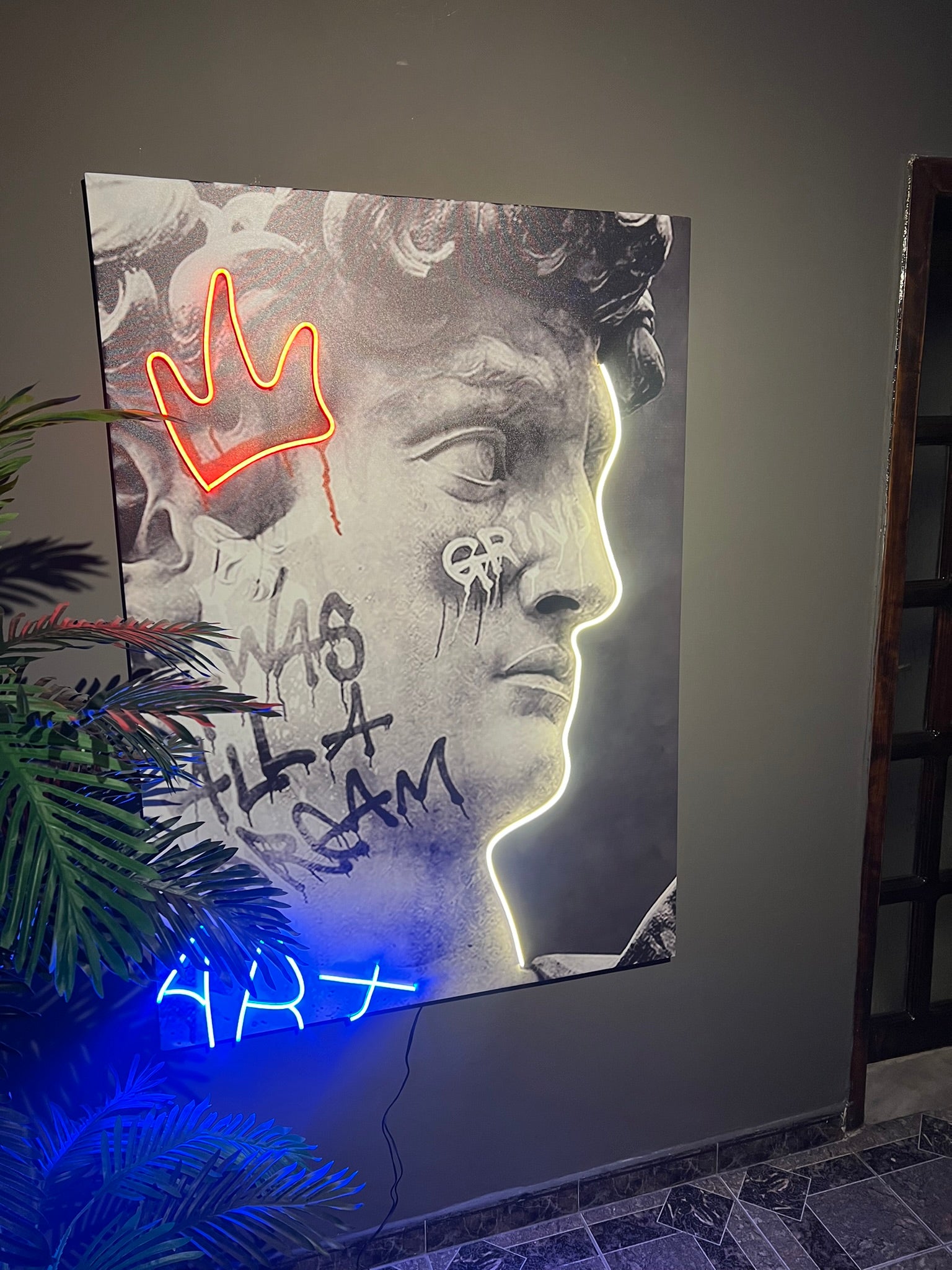 Neon sign with a stylized portrait and text on a wall.