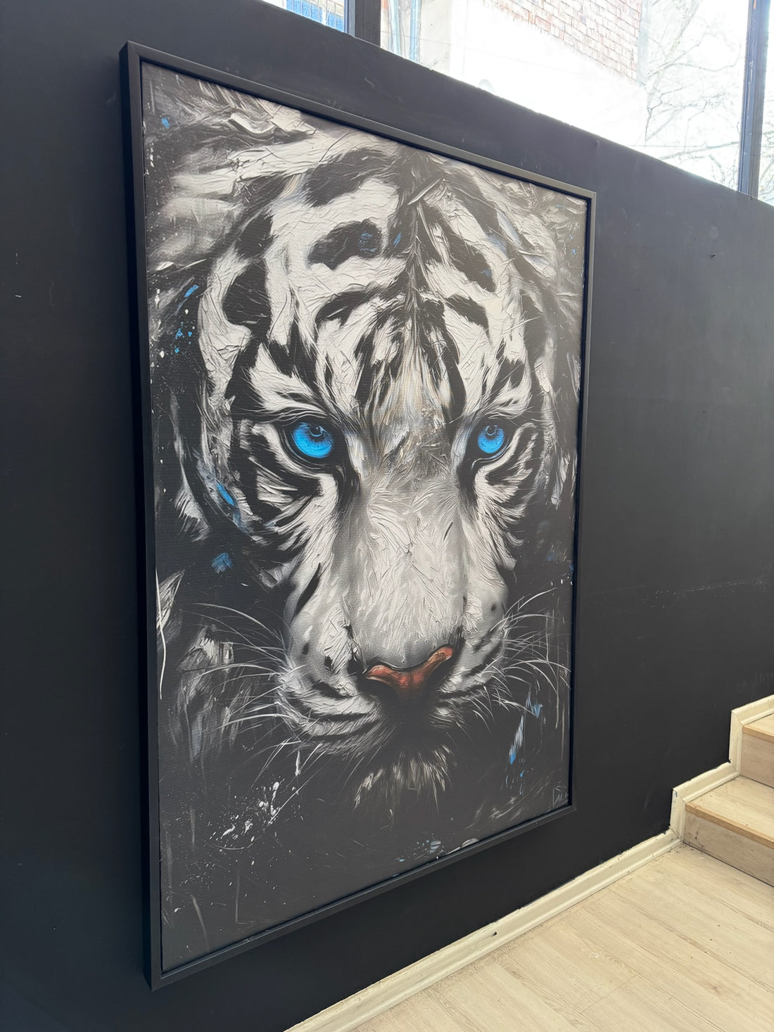 Framed artwork of a tiger with blue eyes on a dark wall.
