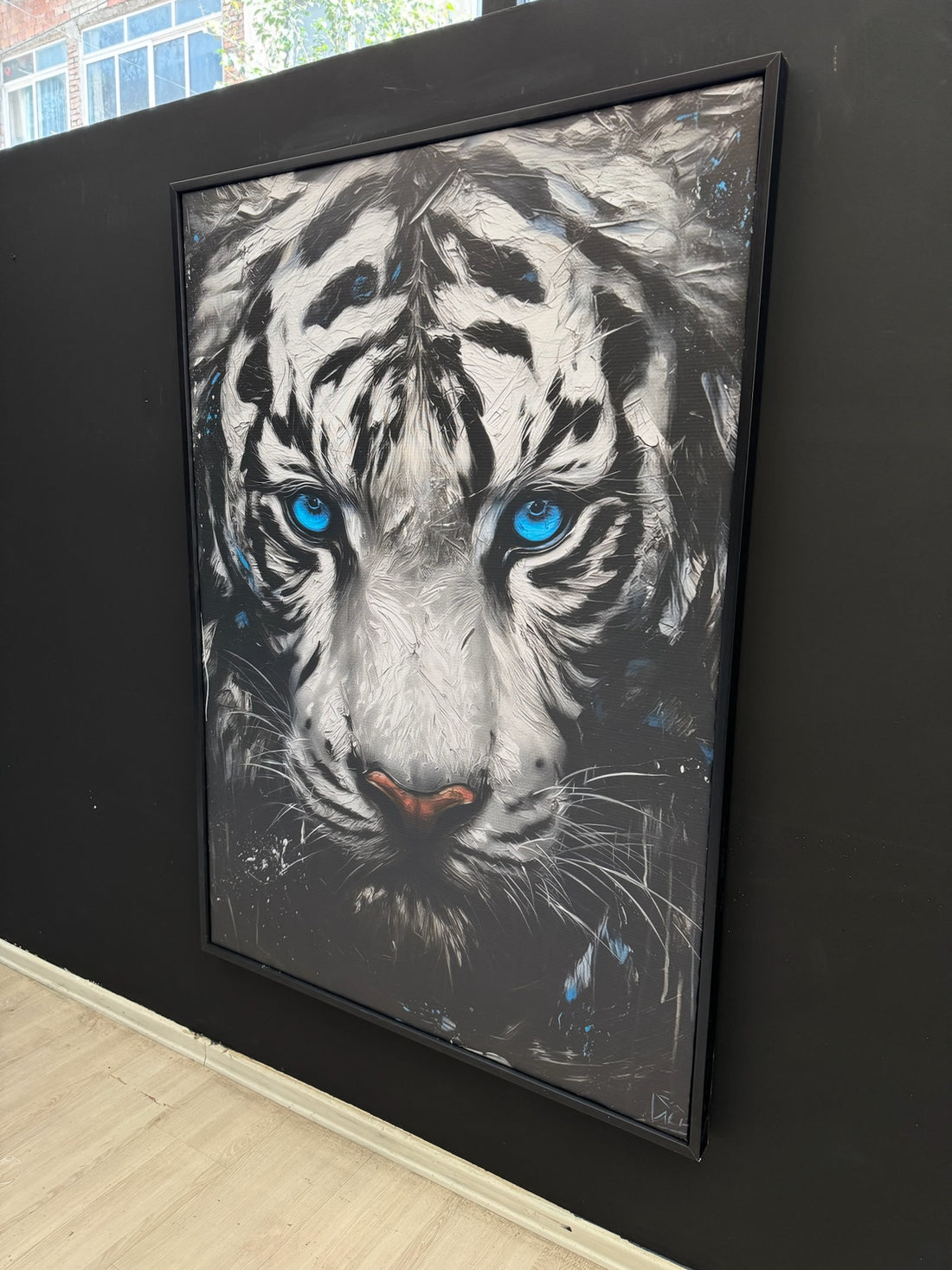 Framed artwork of a tiger with blue eyes on a dark wall.