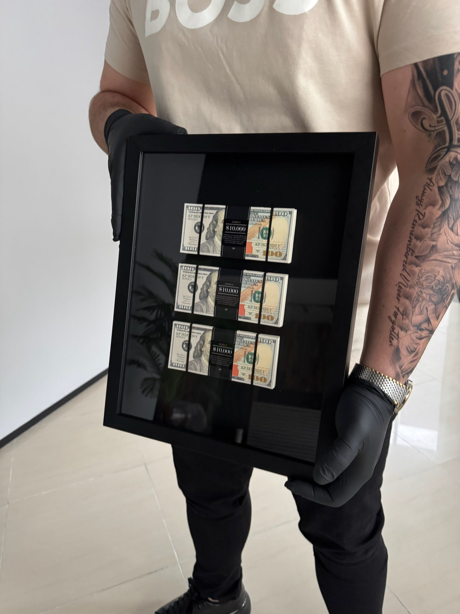 Person holding a framed collection of vintage stamps with a plain background