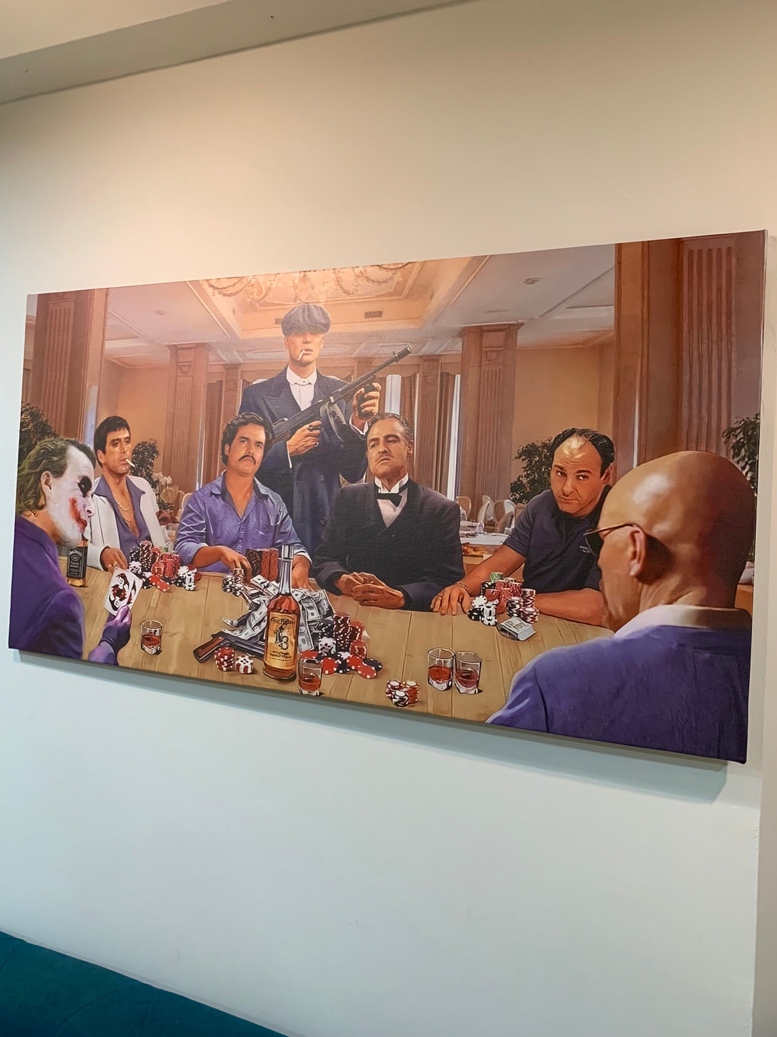 Painting of a group of people around a table with various items on a white wall.