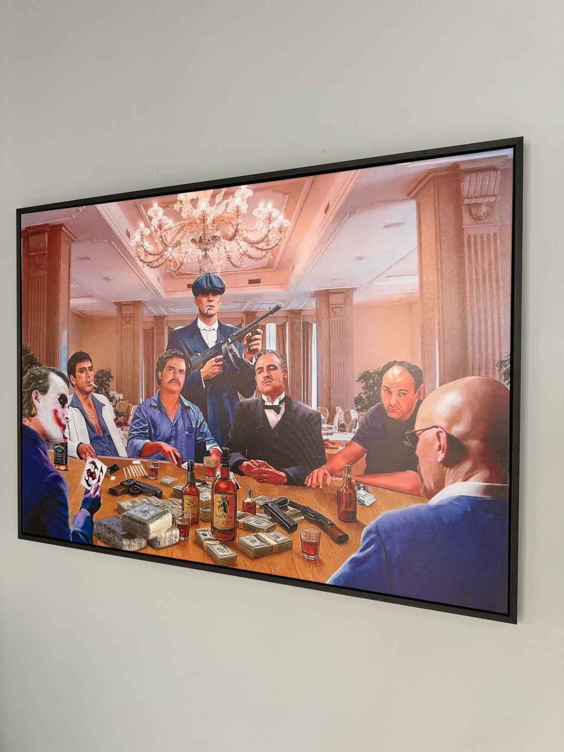 Framed artwork of a group of people around a table with various items, including bottles and guns, in a room setting.