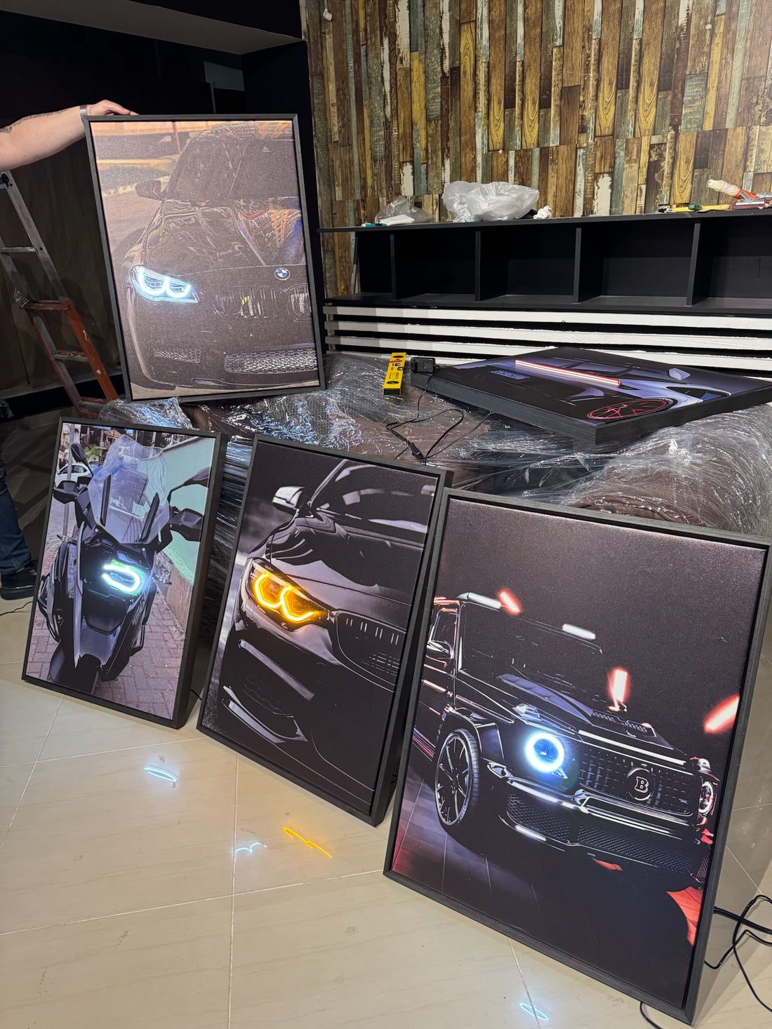 Multiple computer monitors displaying different car models with illuminated headlights on a tiled floor.